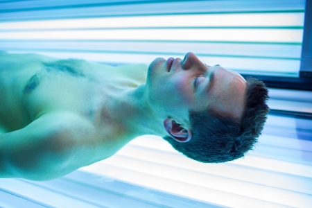 Handsome young man relaxing during a tanning session in a modern solariumの写真素材