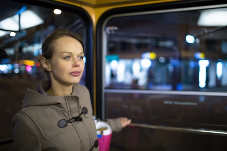 Pretty, young woman on a streetcar tramway, during her evening commute home from work  color toned image の写真素材