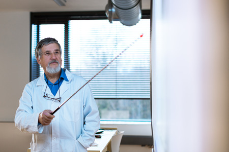 Senior chemistry professor giving a lecture in front of classroom full of students の写真素材