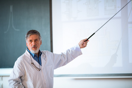 Senior chemistry professor giving a lecture in front of classroom full of students 