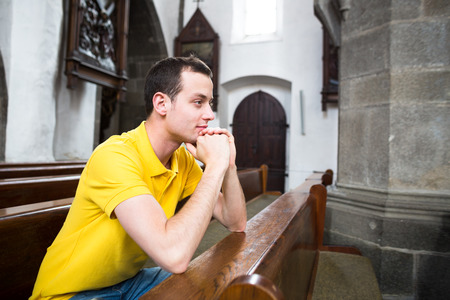Handsome young man praying in a churchの写真素材