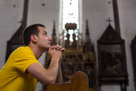 Handsome young man praying in a churchの写真素材