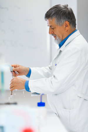Senior male researcher carrying out scientific research in a lab (shallow DOF; color toned image)の写真素材