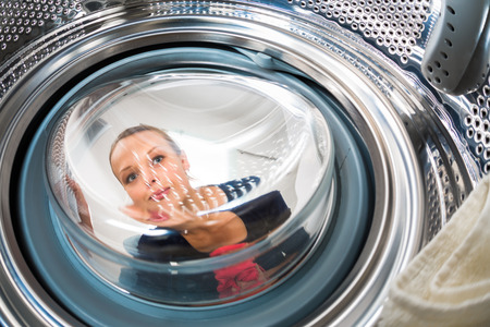 Housework: young woman doing laundry (shallow DOF; color toned image)の写真素材