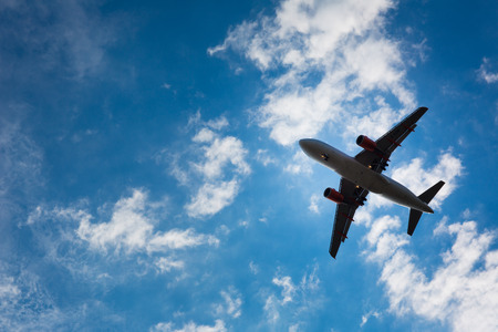 Dark silhouette of an airplane flying over the blue skiesの写真素材