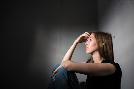 Young woman suffering from a severe depression (very harsh lighting is used on this shot to...