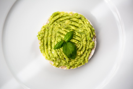 Fresh avocado guacamole on rice bred with basilの写真素材