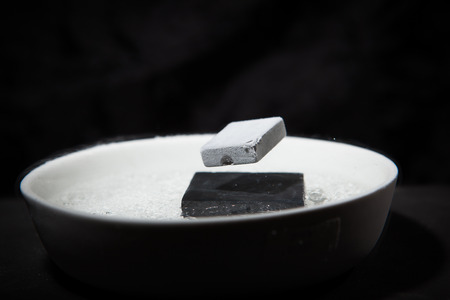 Physics in action - experiment with supraconductive materials, when cooled down by liquid nitrogen, these magnets are strong enough to make each other levitateの写真素材