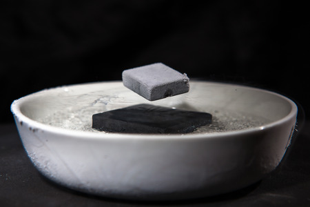 Physics in action - experiment with supraconductive materials, when cooled down by liquid nitrogen, these magnets are strong enough to make each other levitateの写真素材