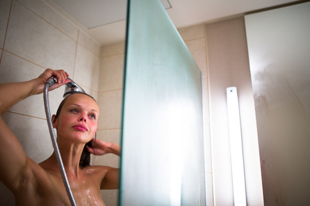 Young woman washing her hair with shampoo, taking a hot long shower