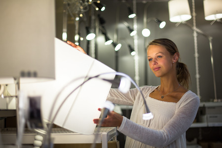 Pretty, young woman choosing the right light for her apartment in a modern home furnishings store...