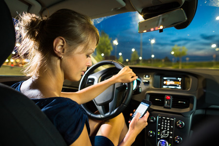 Driving a car at night - pretty, young woman driving her modern car at night, in a city 