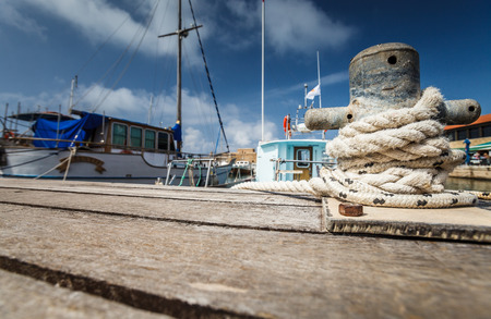 Boat docking point at a marina - rope fixed around a belay in a small harbor