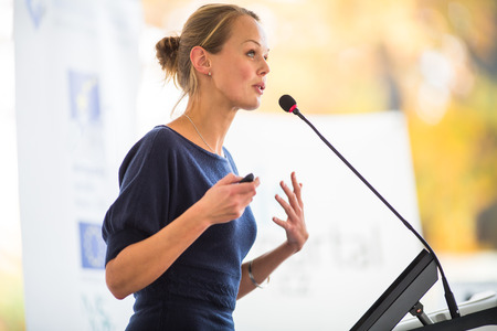 Pretty, young business woman giving a presentation in a conference/meeting setting (shallow DOF; color toned image)の写真素材