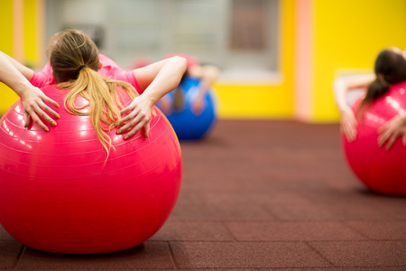 Group people in a pilates class at the gym - young woman with gymball at fitness training (shallow DOF, color toned image)の写真素材