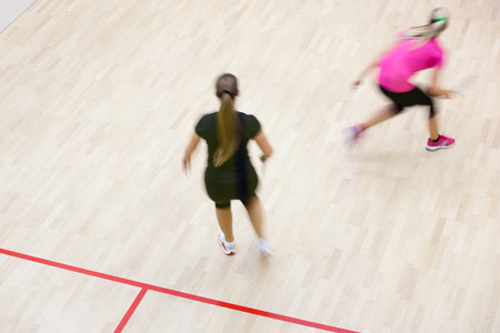 Two female squash players in fast action on a squash court (motion blurred image; color toned image)の写真素材