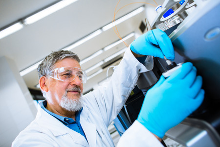 Senior male researcher carrying out scientific research in a lab (shallow DOF; color toned image)の写真素材
