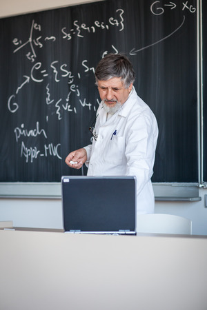 Senior chemistry professor writing on the board while having a chalk and blackboard lecture (shallow DOF; color toned image)の写真素材