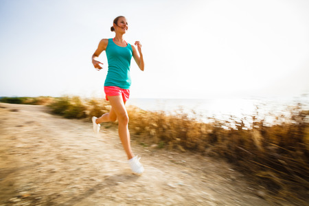 Young woman on her evening jog along the seacoast (motion blurred image)の写真素材