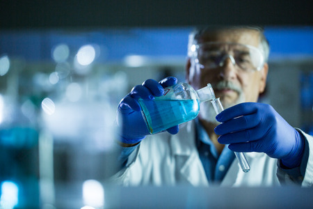 Senior male researcher carrying out scientific research in a lab (shallow DOF; color toned image)