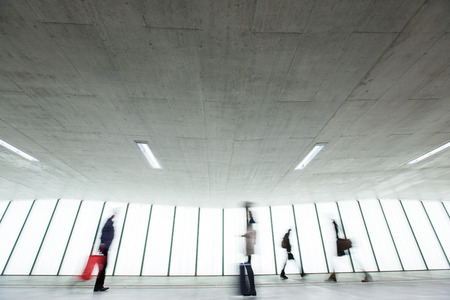 Airport rush: people with their suitcases walking along a corridor (motion blurred image; color toned image)の写真素材