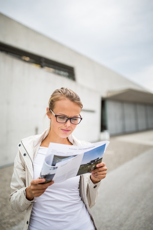 Happy young female tourist with map in the city (color toned image; shallow DOF)の写真素材
