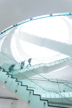 People inside a modern building walking up the stairs (color toned image; motion blurred image)の写真素材