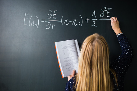 Pretty, young college student writing on the chalkboard/blackboard during a math classの写真素材