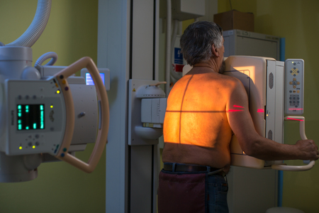 Healthcare Concept - Senior male patient undergoing an X-ray examination in a modern hospitalの写真素材