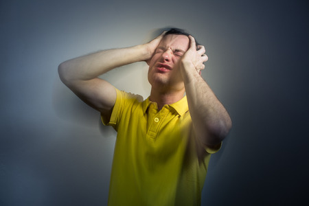 Young man suffering from an intense headache/migraine/anxiety attack - color toned imageの写真素材