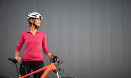 Pretty, young woman biking on a mountain bike enjoying healthy active lifestyle outdoors in summer (shallow DOF)の写真素材