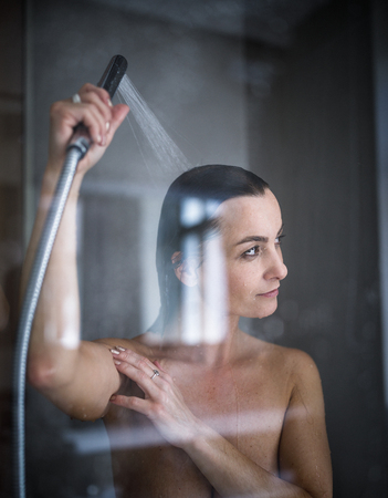 Woman taking a long hot shower washing her hair in a modern design bathroom