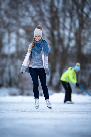 Young woman ice skating outdoors on a pond on a freezing winter dayの写真素材