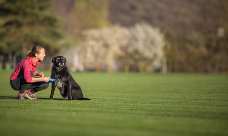 Young woman with her black dog  outdoor, in a park playing frisbee - shallow DOF, sharp focusの写真素材