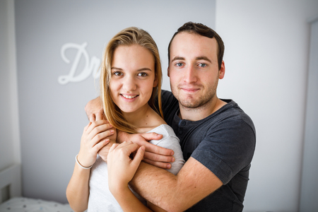 Brother and sister posing for a photo together. Hugging and smiling, feeling caring and loved.の写真素材