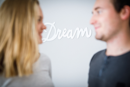 A boy and a girl looking at each other with a word DREAM in focus on the background