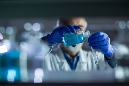Senior male researcher carrying out scientific research in a lab (shallow DOF; color toned image)の写真素材