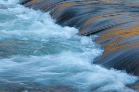 Water concept - river water flowing with light reflecting of its surface - long exposure shot