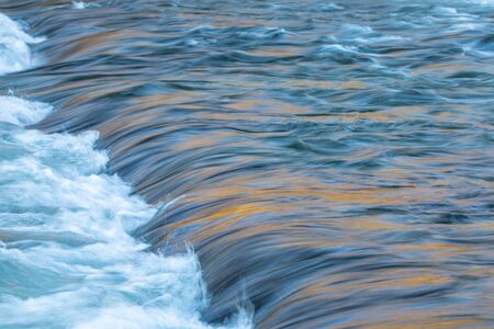 Water concept - river water flowing with light reflecting of its surface - long exposure shot