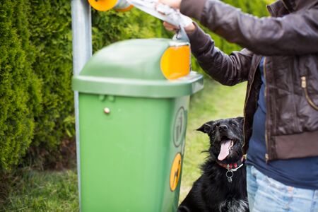 Do not let your dog foul! - Young woman grabbing a plastic bag in a park to tidy up after her dog laterの写真素材