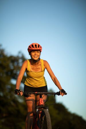 Pretty, young woman biking on a mountain bike enjoying healthy active lifestyle outdoors in summer (shallow DOF)の写真素材