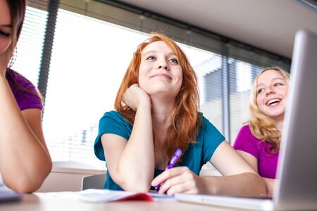 Students in classroom - young pretty female college student sitting in a classroom full of students during class (color toned image; shallow DOF)の写真素材