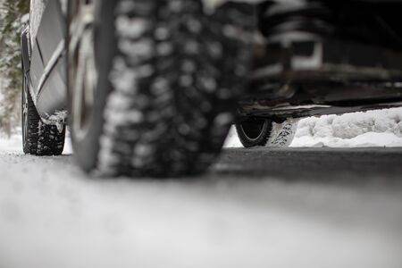 Car on a snowy winter road amid forests - using its four wheel drive capacities to get through the snowの写真素材