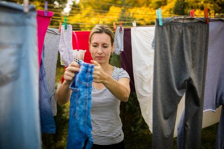 Young woman putting laundry on a rope in her garden,  taking great care of her family on a daily basisの写真素材