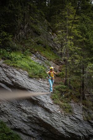 Pretty, female climber on a via ferrata - climbing on a rock in Swiss Alps