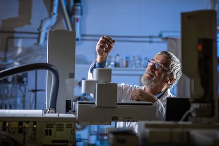 Senior scientist in a chemistry lab carrying out research - looking at gas chromatography samples, preparing the analysis on a modern gas chromatographer (color toned image)の写真素材