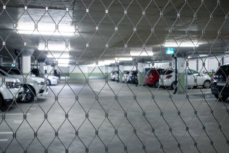 Gated underground parking. Cars parked in a garage with no people. Many cars in parking garage...