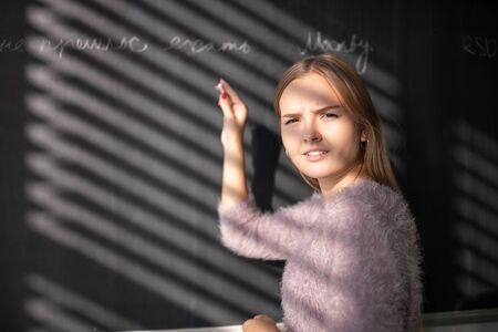 Pretty, young female student in front of a blackboard during classの写真素材