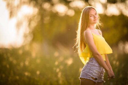 Portrait of young  woman with radiant clean skin lying down amid flowers on a lovely meadow on a spring/summer dayの写真素材
