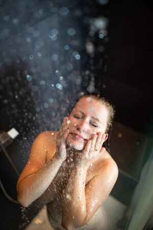 Pretty,young woman taking a long hot shower in a modern bathroomの写真素材